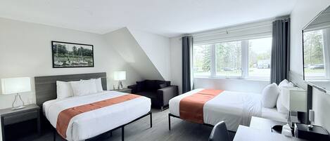 Habitación de hotel con dos camas, un escritorio, una silla, un sofá y un ventanal grande.