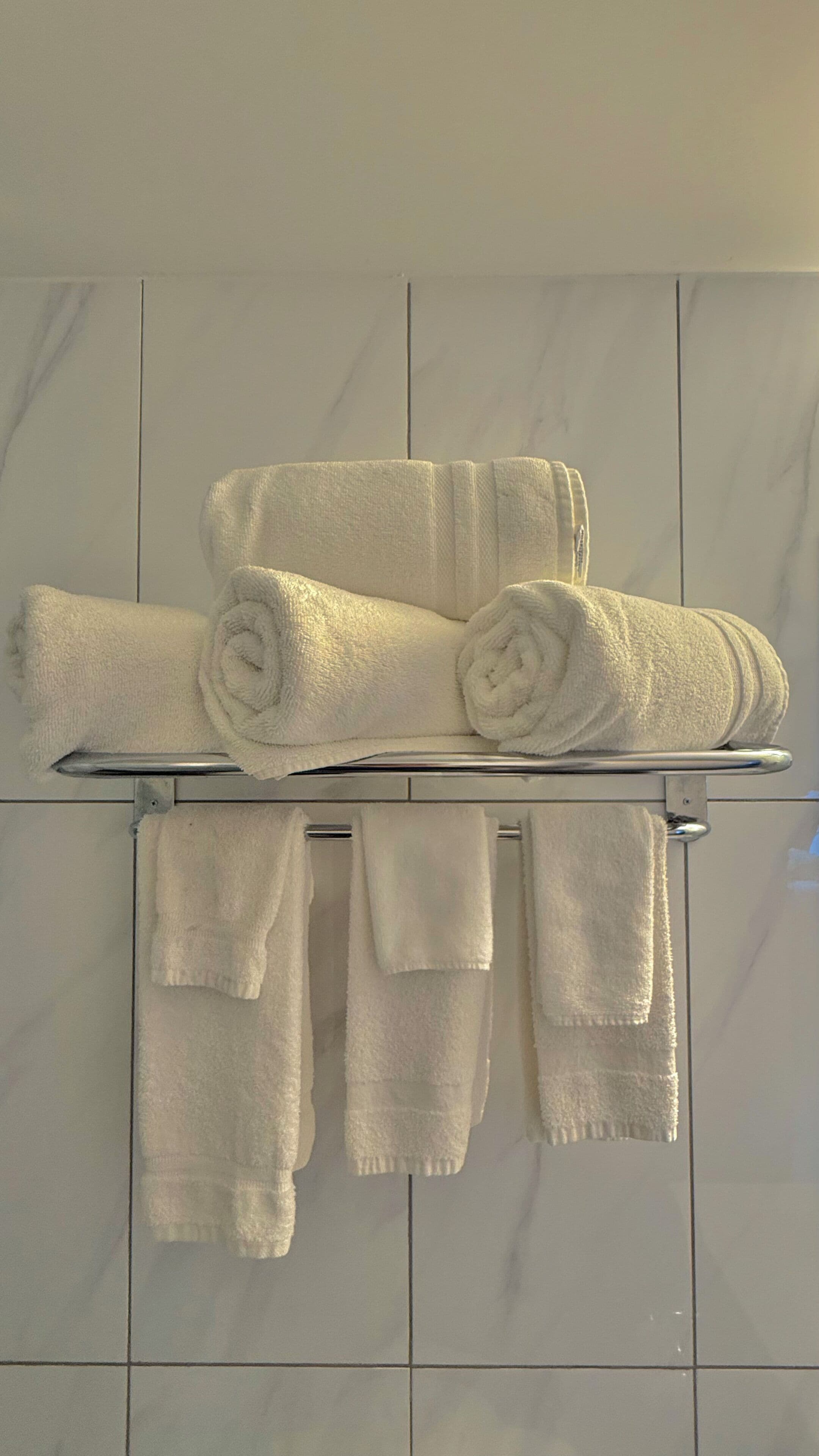 A bathroom with a towel rack holding several white towels.