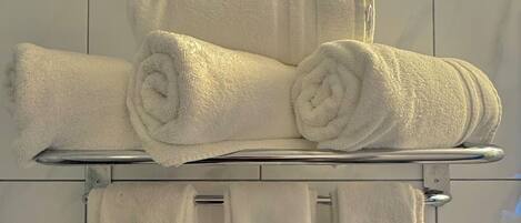 A bathroom with a towel rack holding several white towels.