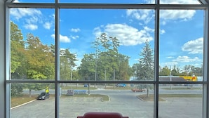 A room with a large window, a red chair, and a carpeted floor. - Amber Hotel (Lambton Shores)