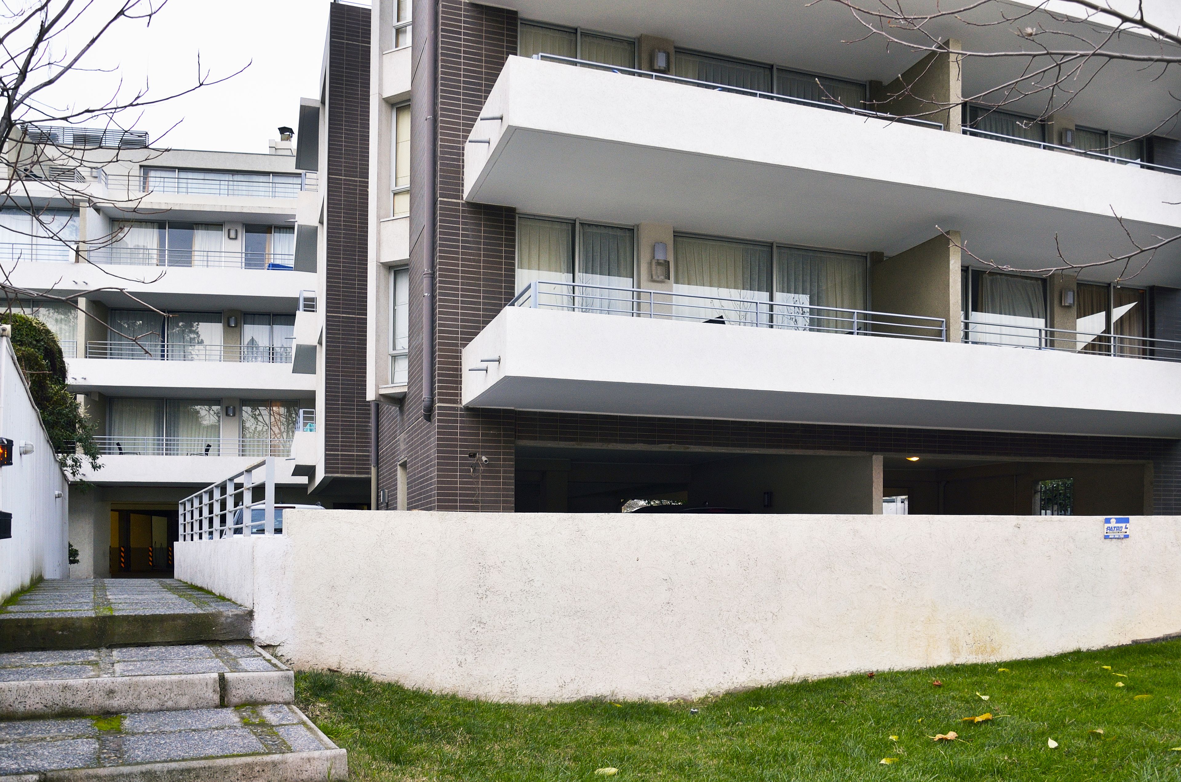 Ein mehrstöckiges Wohngebäude mit Balkonen, einer Garage und einem kleinen Vorgarten.