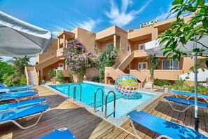 A pool area with lounge chairs, a pool, and a building labeled "SOLONI". - Solon Apartments (Platanias)