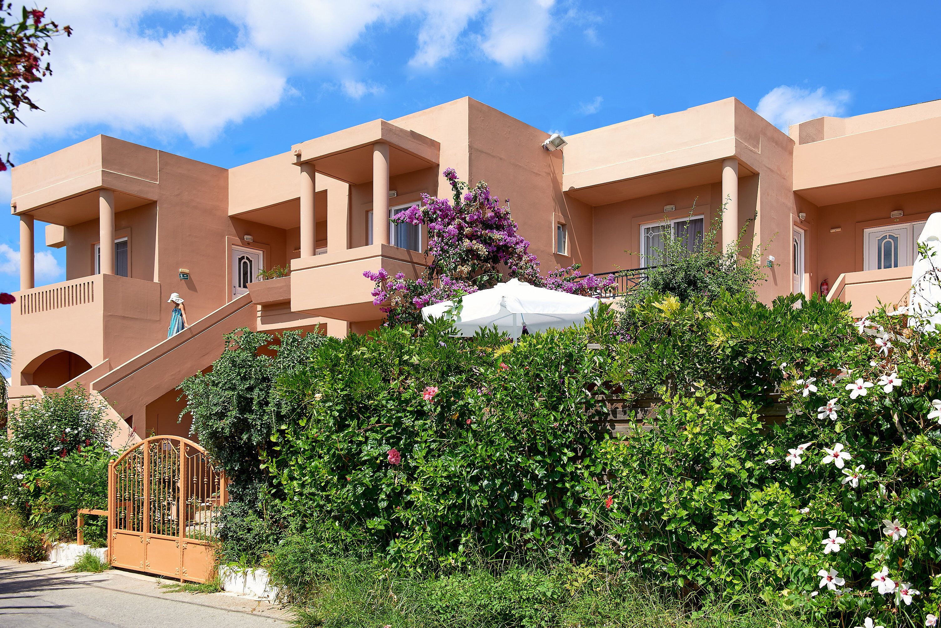 A multi-story building with balconies and a gated entrance.