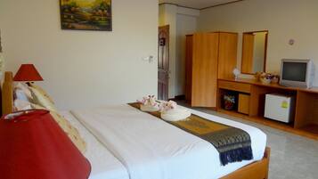 A hotel room with a bed, a desk with a computer, a TV, and a painting on the wall.