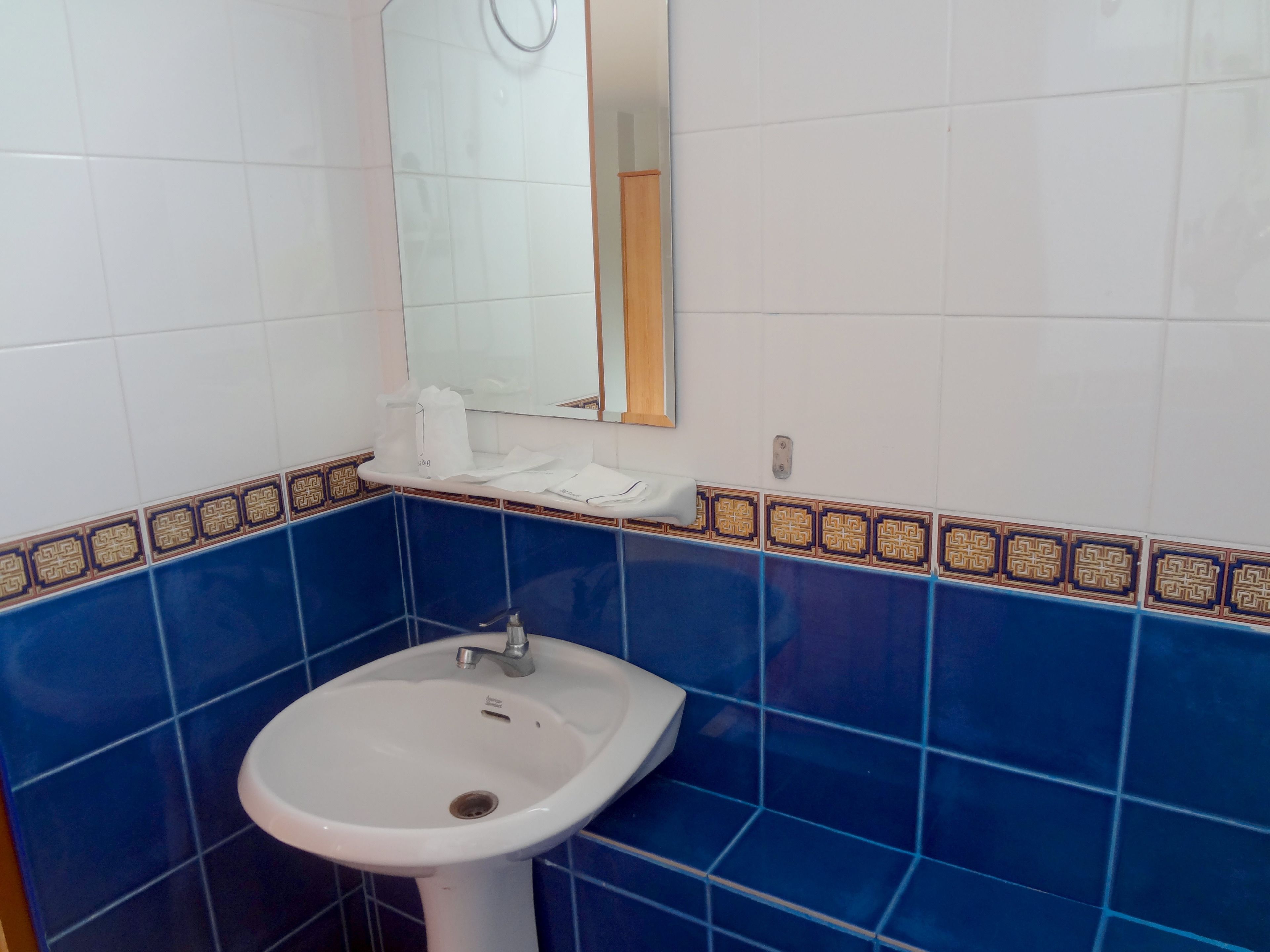 Une salle de bain avec un lavabo blanc, des carreaux bleus et un miroir.