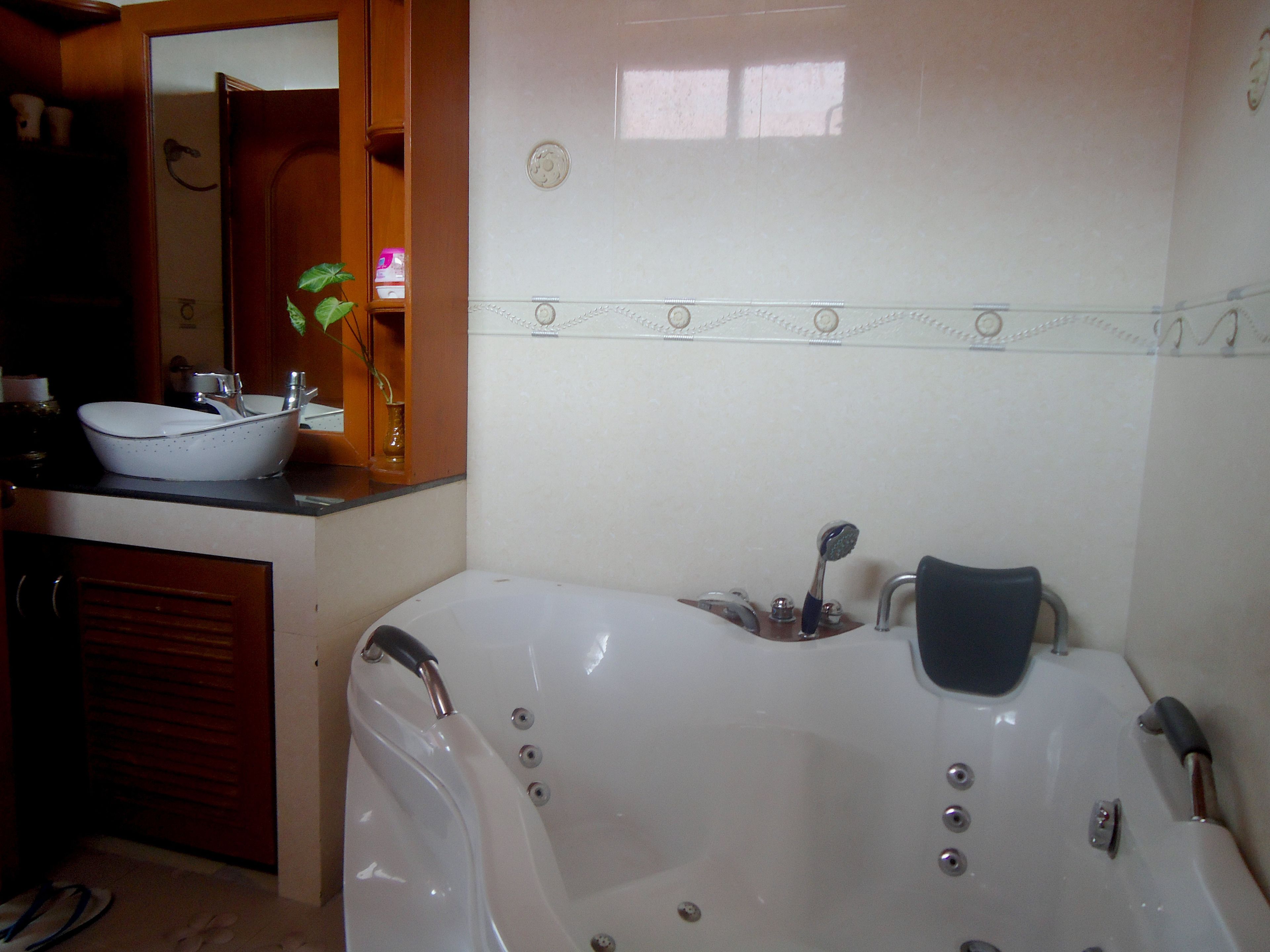 A bathroom with a white bathtub, a sink, and a mirror.