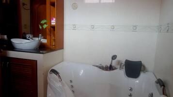 A bathroom with a white bathtub, a sink, and a mirror.