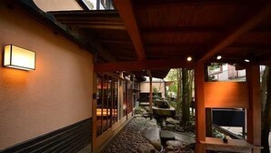 En korridor med en stenbelagt sti, træbjælker og et lille vandelement.
