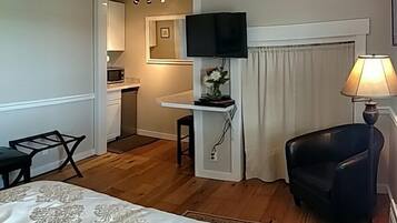 Hotellihuone, jossa on sänky, työpöytä, tuoli, televisio ja lamppu.