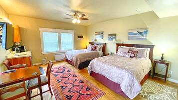 A bedroom with two beds, a ceiling fan, a desk, and a chair.