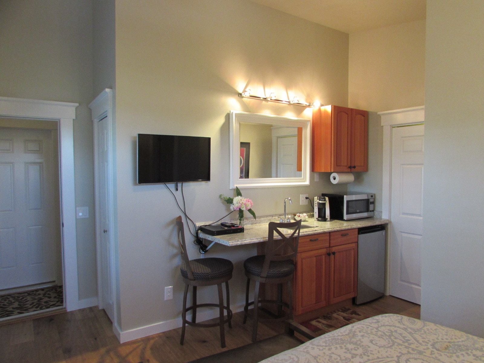 Cocina compacta con televisión, microondas, pileta y muebles de madera.