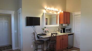 A compact kitchen with a TV, a microwave, a sink, and wooden cabinets.