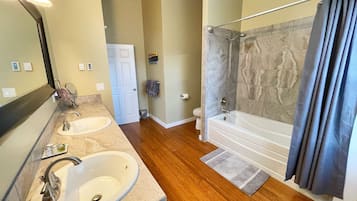A bathroom with two sinks, a bathtub, and a shower.