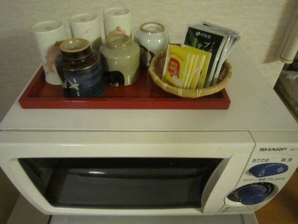 A microwave with a red tray on top, containing various items like a bottle, a jar, and some packaged goods.