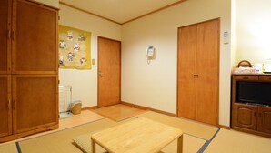 Una habitación con suelo de tatami, armarios de madera, una mesita pequeña y un teléfono instalado en la pared.
