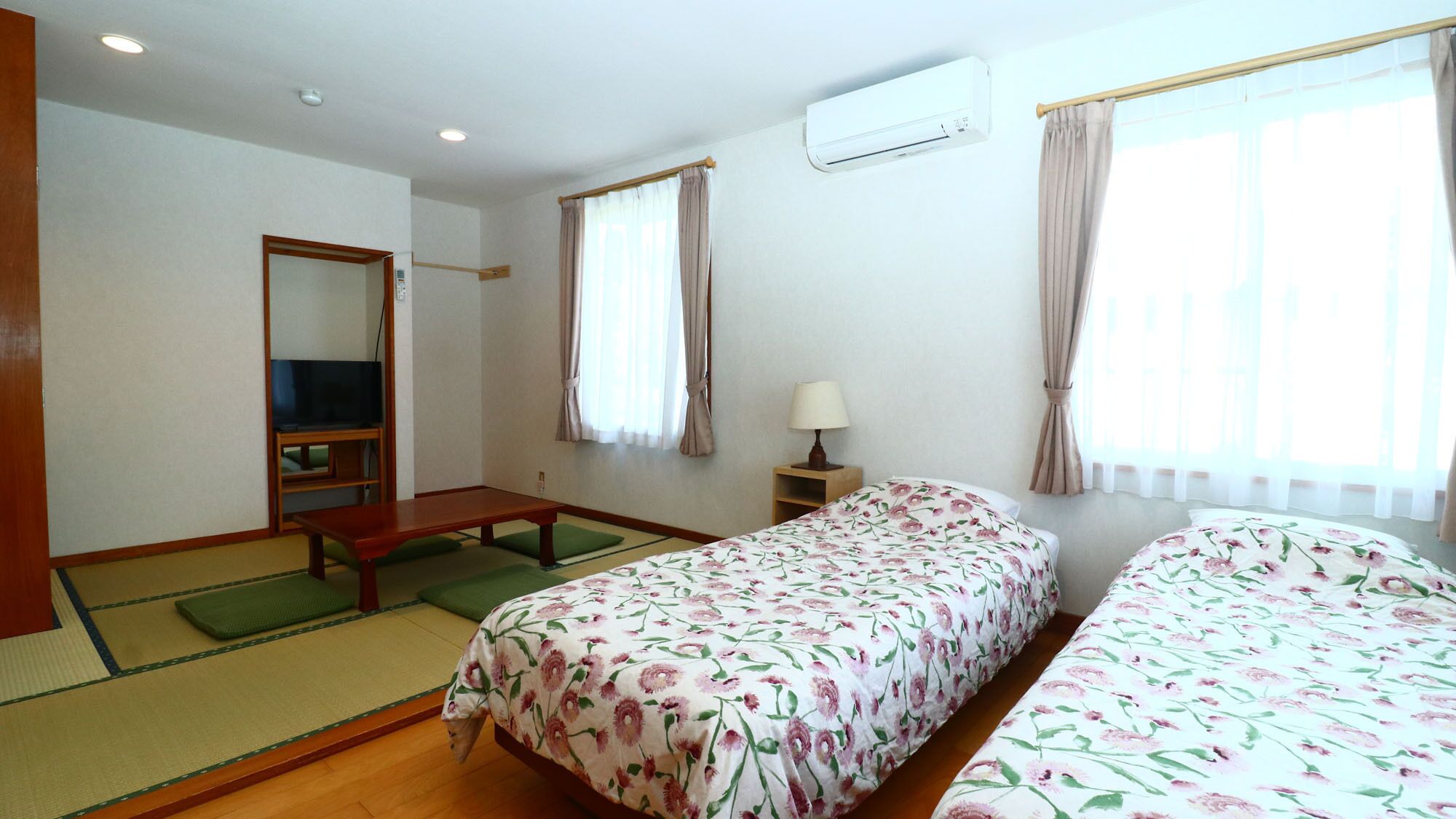 Una habitació d'hotel amb un llit, una televisió, una taula i una finestra.