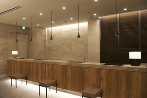 A modern bathroom with three sinks, wooden paneling, and pendant lighting.