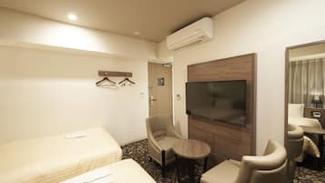 Une chambre d’hôtel avec deux lits, une télévision, une chaise, une petite table et un miroir.