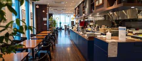 A restaurant with wooden tables and chairs, a counter with a menu, and a kitchen area.