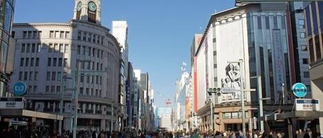 A busy urban street with historic buildings, a clock tower, and pedestrian crossings.
