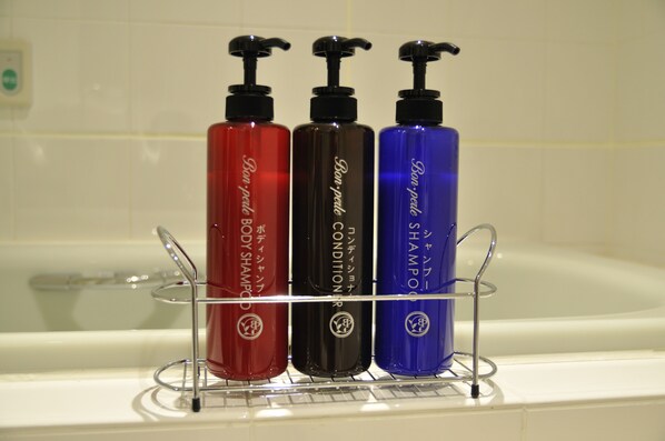 Three bottles of body lotion on a rack in a bathroom.