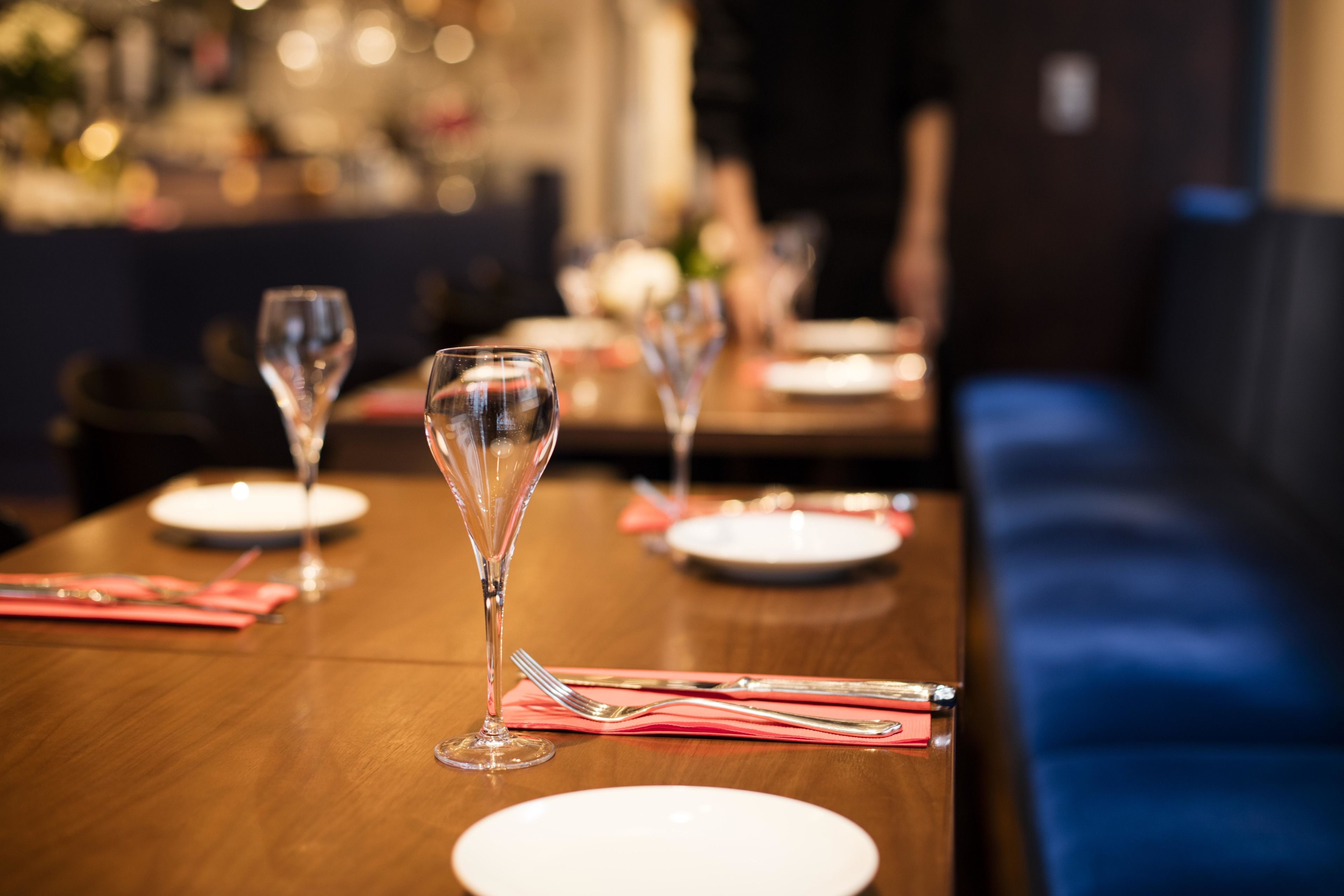 Una mesa de comedor con vasos transparentes, platos y cubiertos.