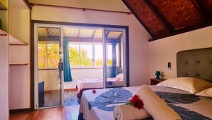 Un dormitorio con cama, mesita de noche, ventana y puerta corredera que da a un balcón.