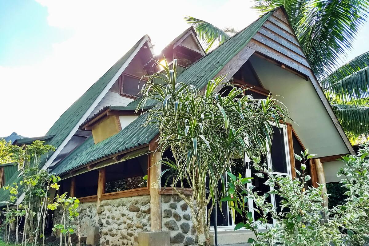 A traditional house with a stone foundation, a sloped roof, and a wooden porch.