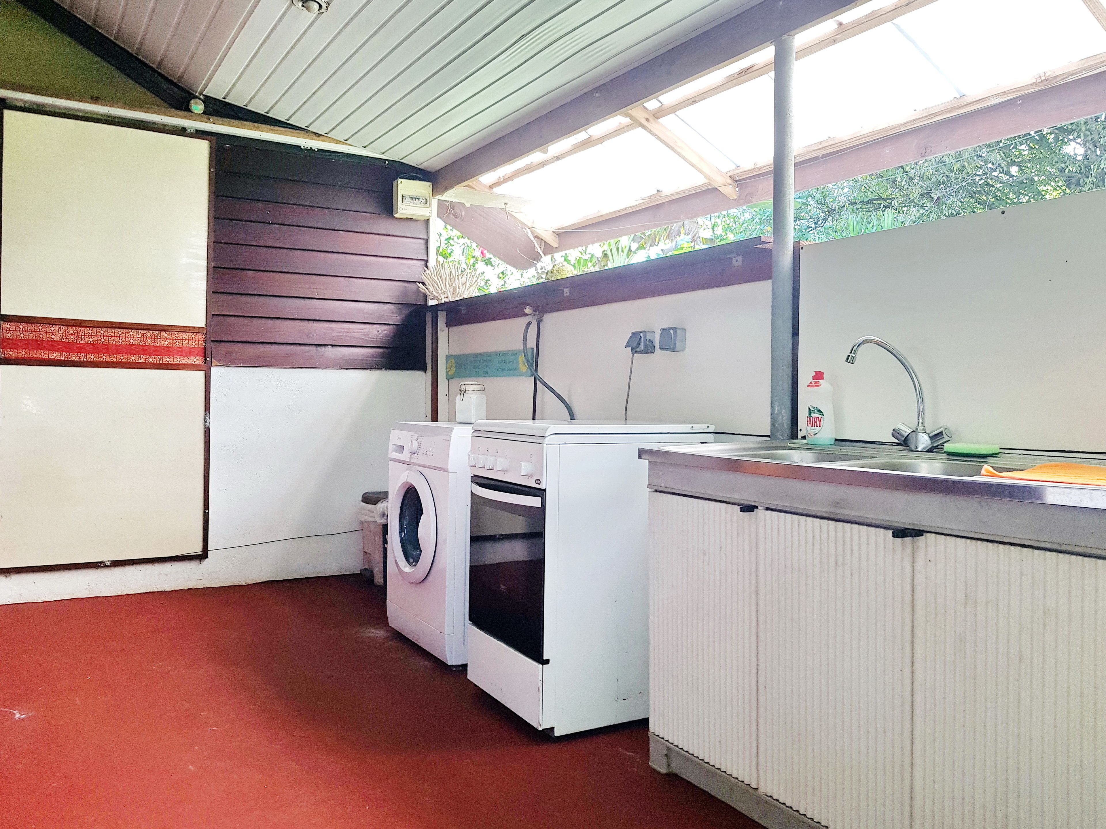Een praktische keuken met een wasmachine, een spoelbak en een kleine koelkast.