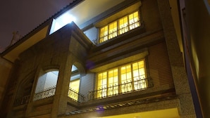 A two-story building with a balcony, a dining area with a table and chairs, and a large window with curtains. - Malia Homestay (Hualien City)