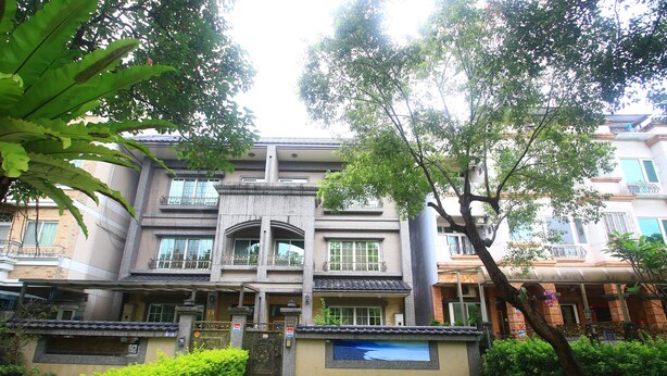 A multi-story residential building with a balcony on the second floor, a well-maintained lawn, and a tree in the foreground. - Malia Homestay (Hualien City)