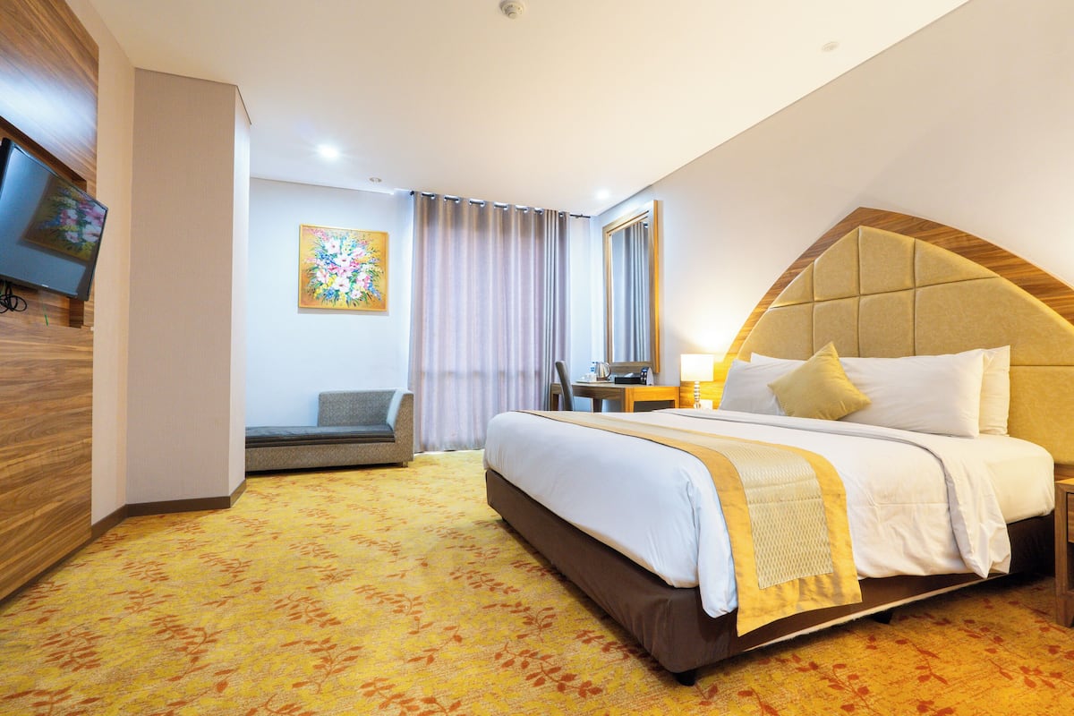 Une chambre d’hôtel avec un grand lit, une télévision, un bureau et une chaise.