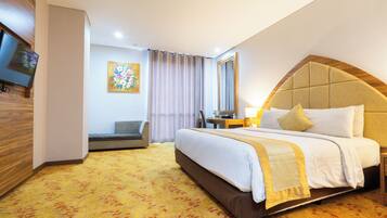 A hotel room with a large bed, a television, a desk, and a chair.