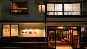 Un edificio japonés tradicional con fachada de tejas, entrada de madera y un letrero con caracteres japoneses.
