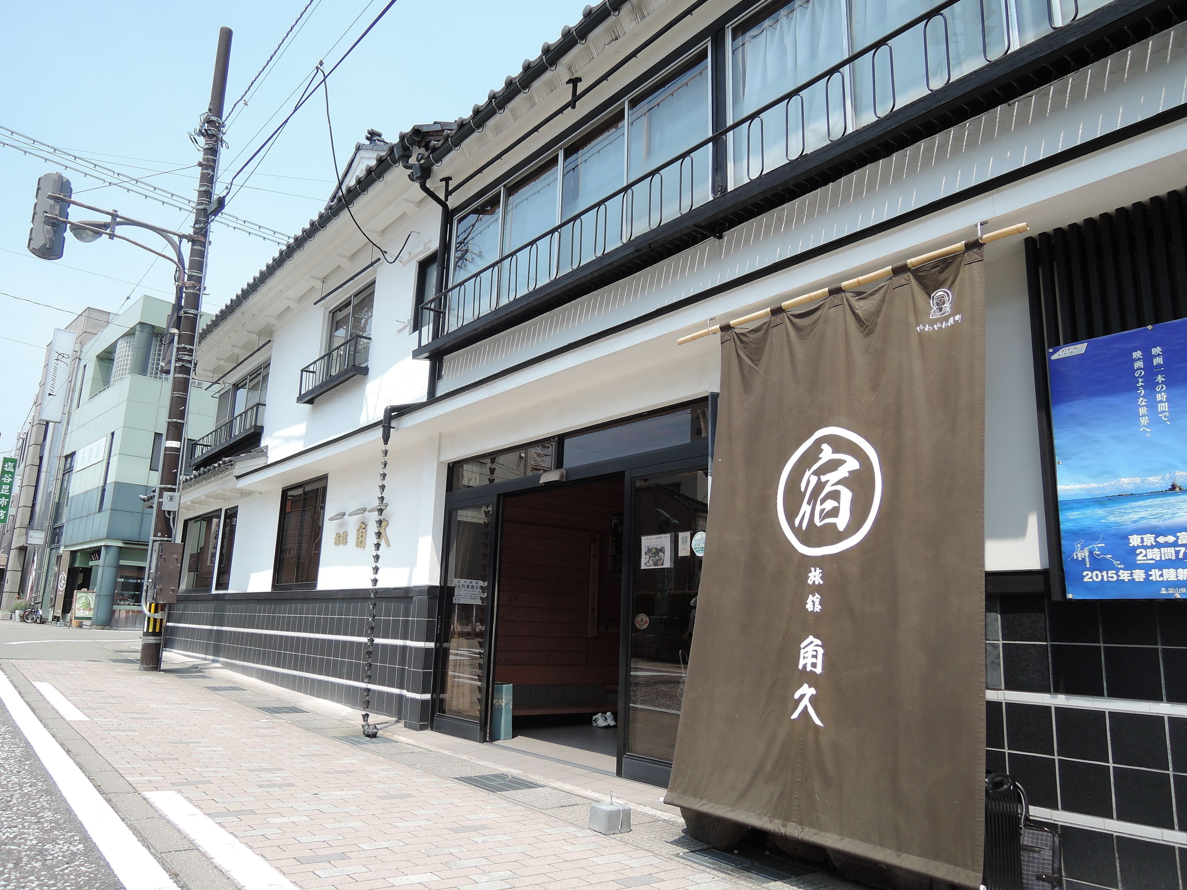 Ein traditionelles japanisches Gebäude mit einer Schaufensterfront und einem großen, braunen Banner mit weißer Schrift.
