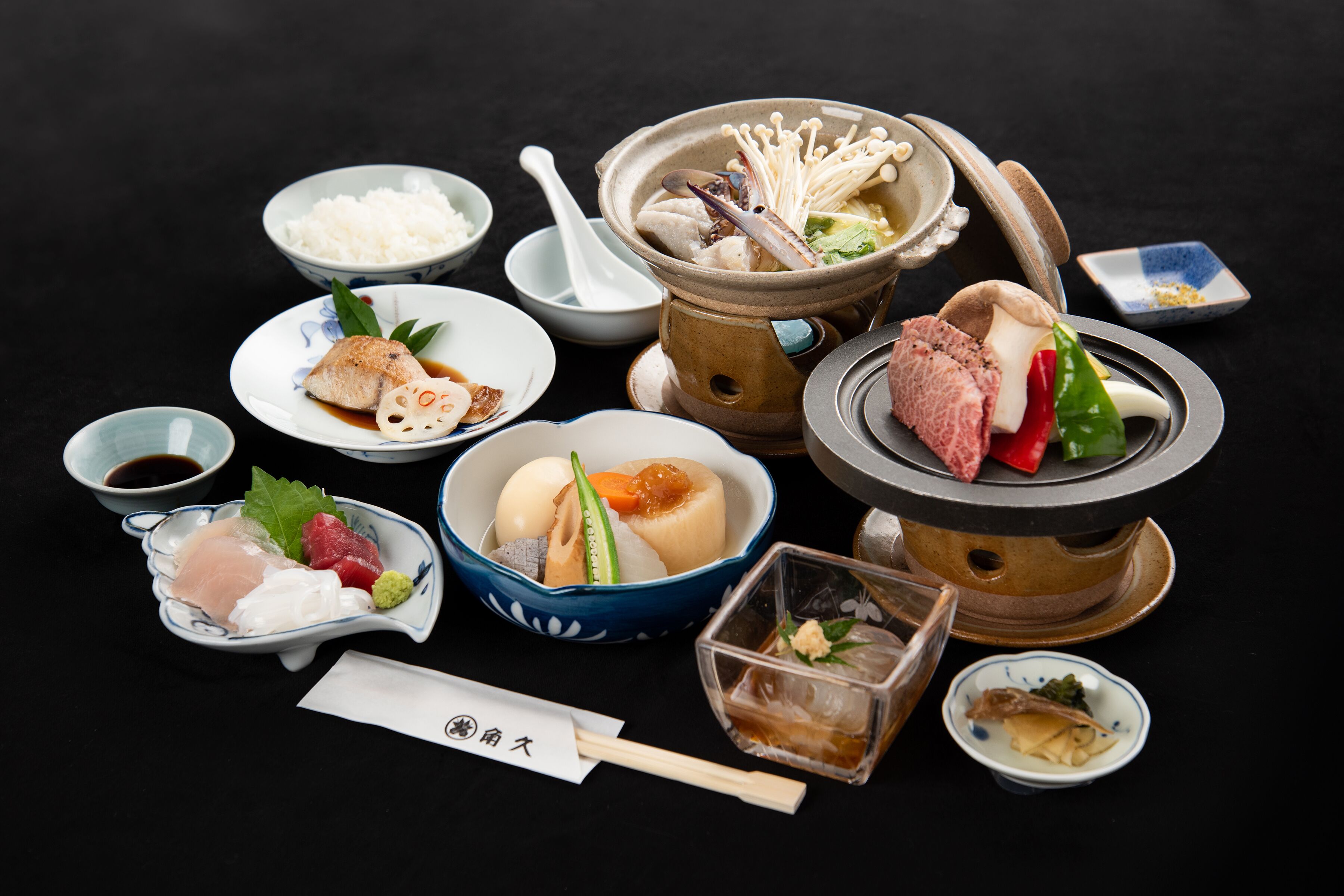 A variety of Japanese dishes including sushi, sashimi, and a hot pot setup.