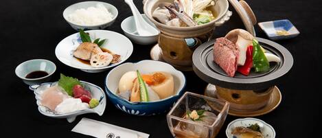 A variety of Japanese dishes including sushi, sashimi, and a hot pot setup.