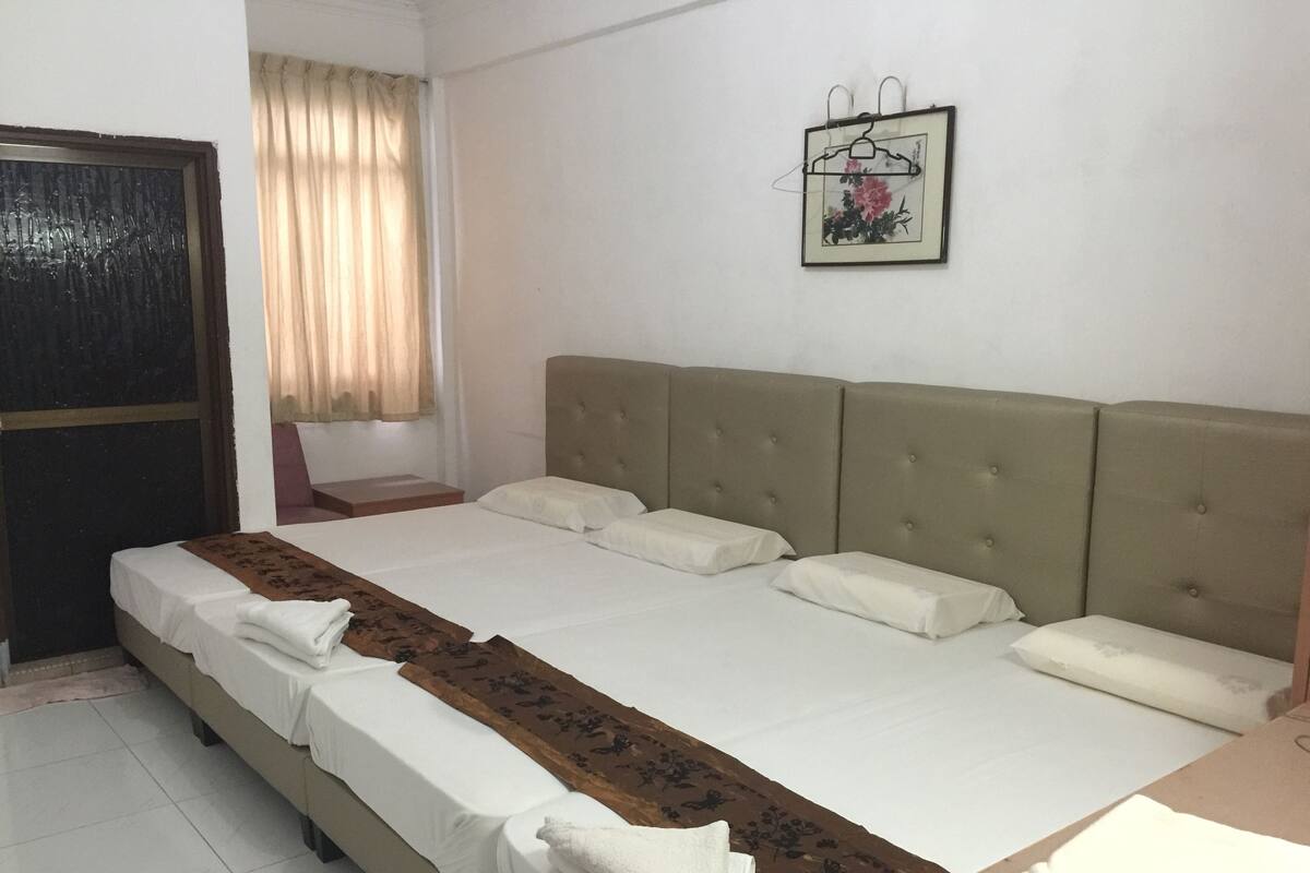 Een hotelkamer met een groot bed, een nachtkastje, een kledingkast en een raam met gordijnen.