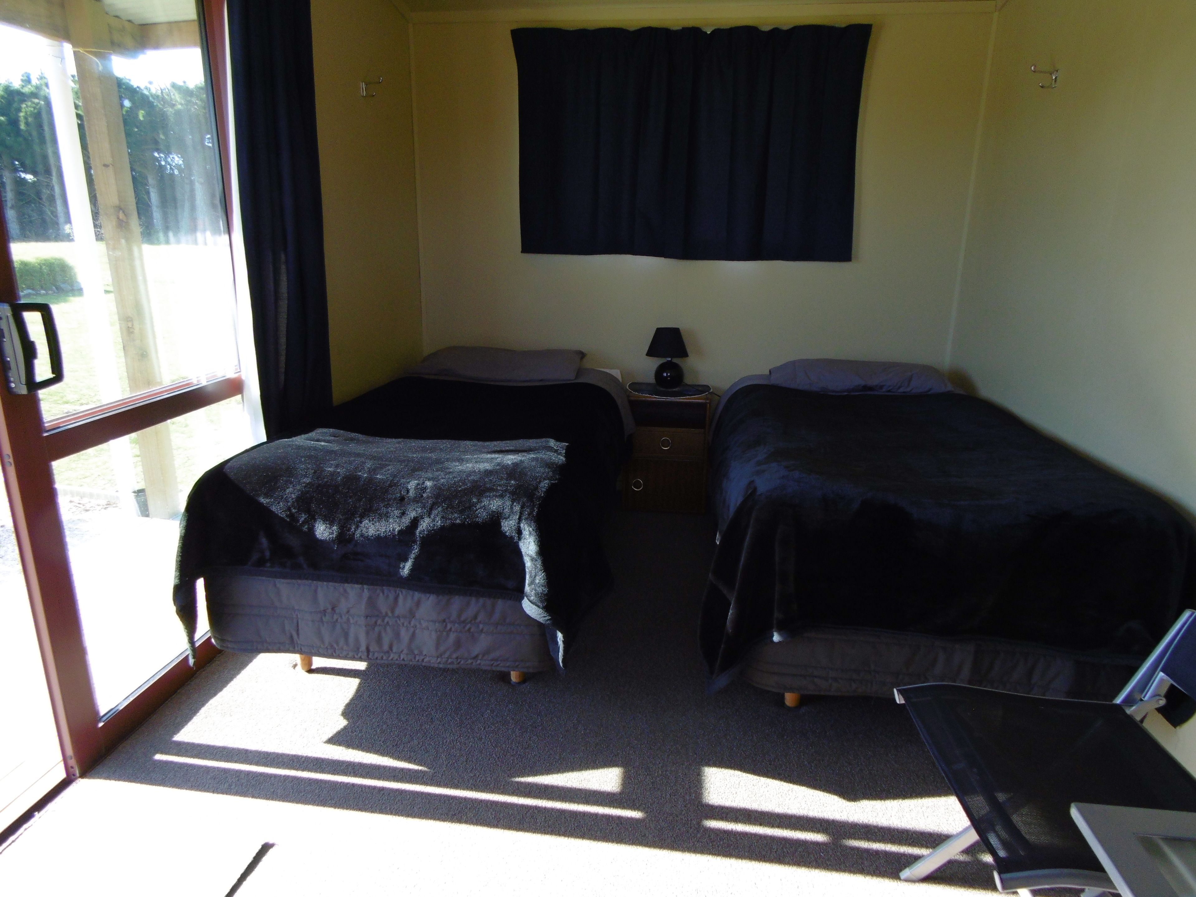 Una habitación con dos camas, un escritorio y una ventana con cortinas.