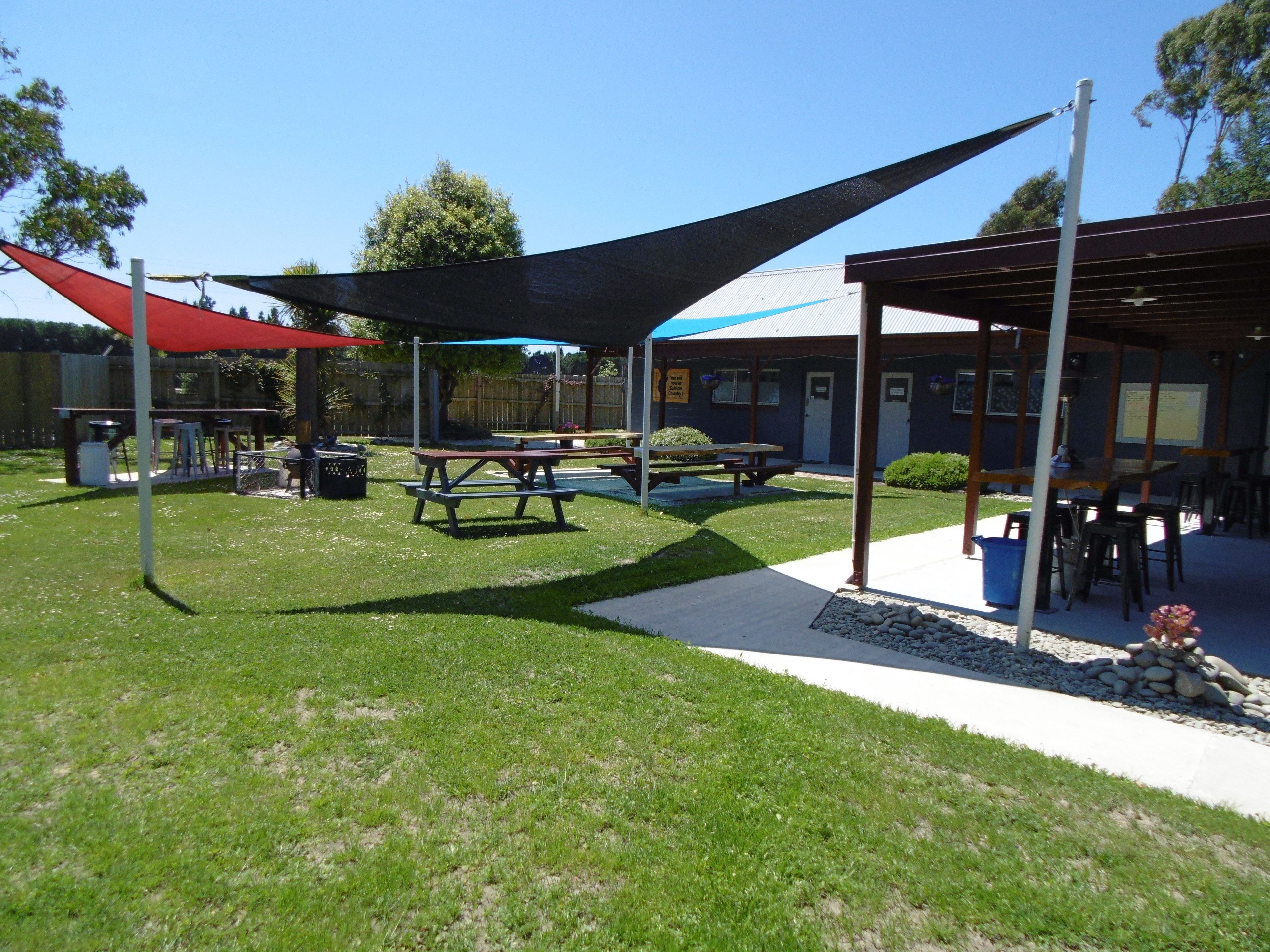 Un área de estar al aire libre cubierta con mesas de picnic y una parrilla.