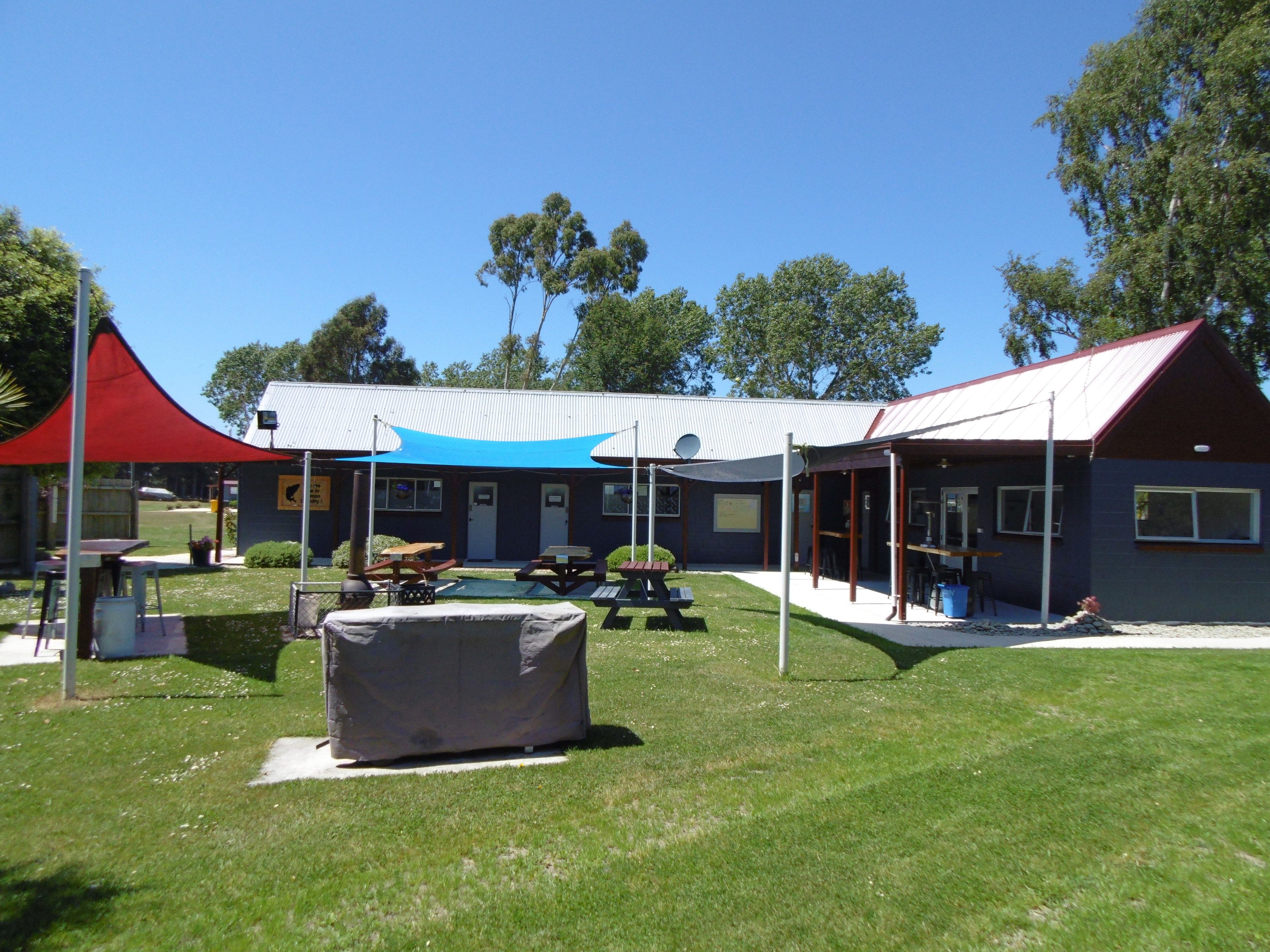 A building with a covered outdoor area, picnic tables, and a barbecue grill.