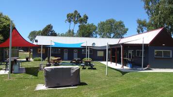 A building with a covered outdoor area, picnic tables, and a barbecue grill.