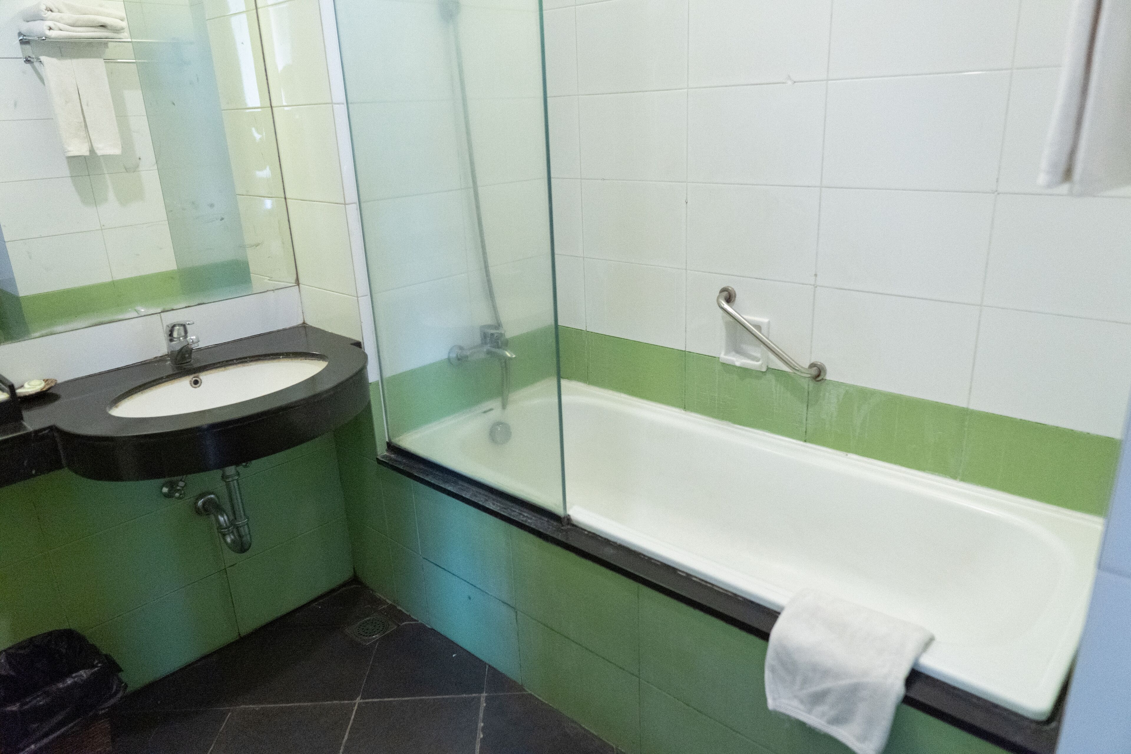 A bathroom with a sink, mirror, and bathtub.
