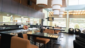 Un restaurante moderno con una barra alargada, varias zonas de estar y amplios ventanales que aportan luz natural.