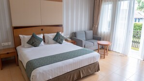 Habitación de hotel con una cama grande, un sofá, una mesita y vistas al exterior.