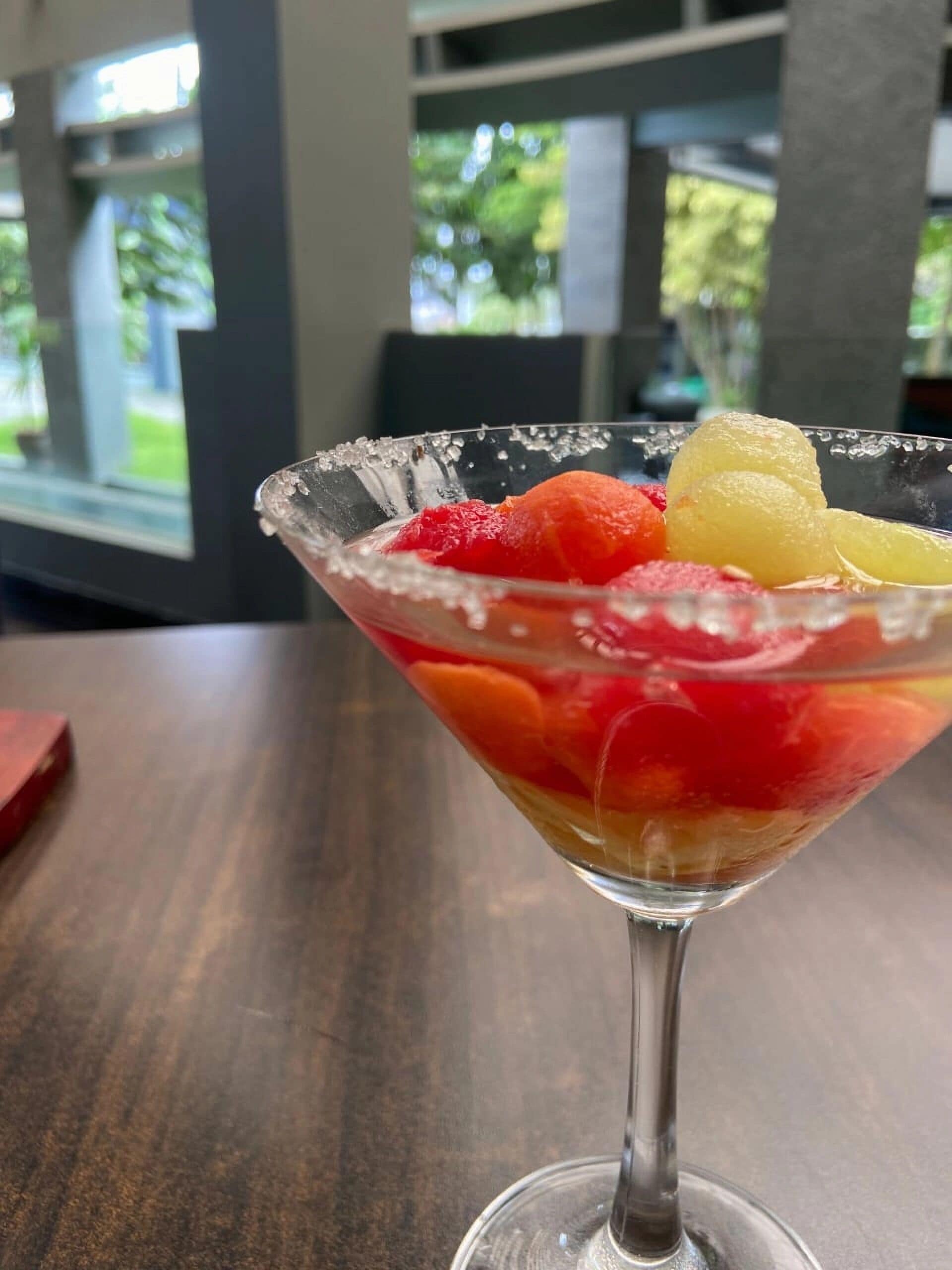 A martini glass with fruit on a table.