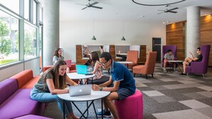 Un espace de détente moderne, doté de sièges et de tables, de grandes fenêtres et de ventilateurs de plafond.