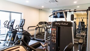 Une salle de sport équipée de tapis de course, d’un vélo d’appartement et d’une machine de musculation de la marque « Body-Solid ».