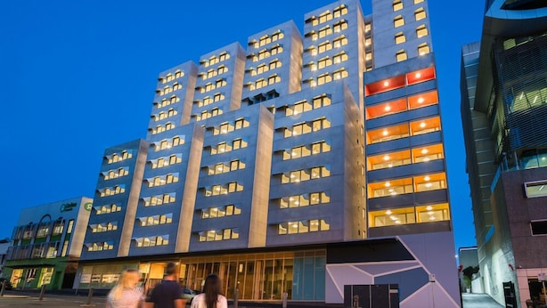 Un hôtel moderne, doté de nombreux étages, de grandes fenêtres et d’une entrée imposante.