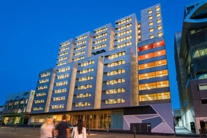 A modern hotel with multiple floors, large windows, and a prominent entrance. - Student Village Melbourne (Carlton)